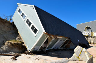 One-story house pushed off its lot and sitting tilted on a beach after Hurricane Irma